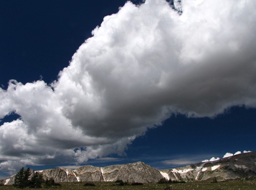 Snowy Mountains Crest with Streaming Cumulus Clouds